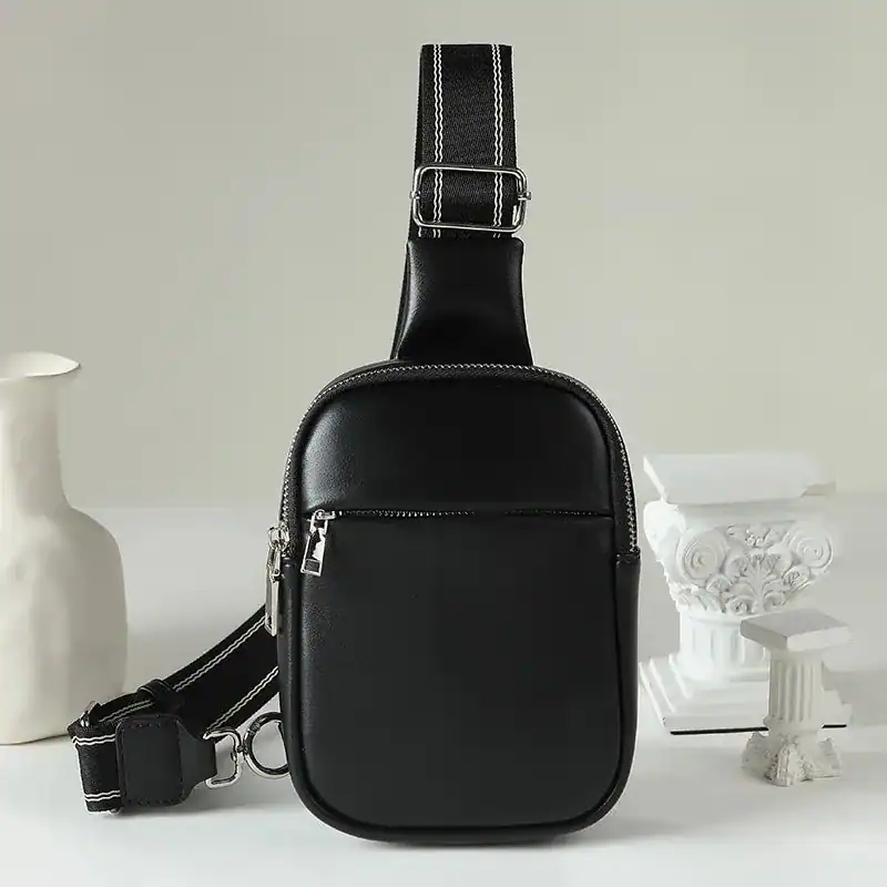 Svart cognac bröstväska med vit kontraststitching och justerbar axelrem.