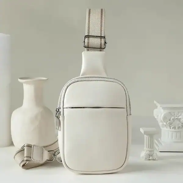 Cognac färgad bröstväska med axelrem, minimalistisk design och praktiskt förvaringsutrymme.