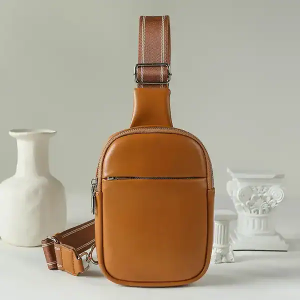 Cognac färgad bröstväska i läder med justerbar axelrem och frontficka.