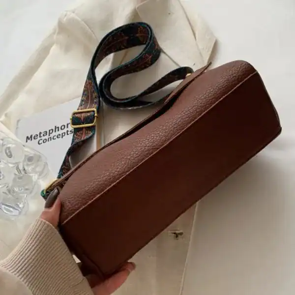 Cognac färgad liten Axelväska med mönstrad axelrem och läderliknande yta.