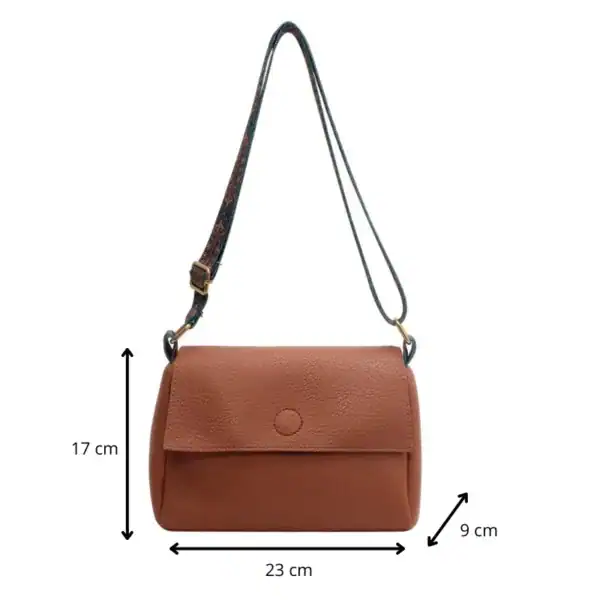 Cognac färgad liten axelväska med mått 23x17x9 cm och mönstrad axelrem.