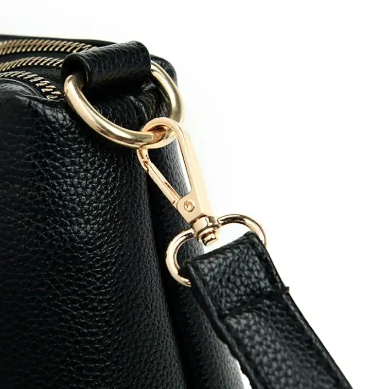 Svart läder crossbody väska med guld detaljer och dragkedja.