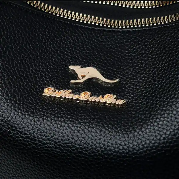 Cognac liten crossbody, svart läder med guld Axelväska logo och dragkedja.