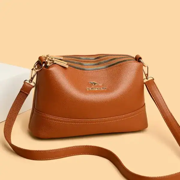 Cognac färgad liten crossbody axelväska med dragkedja och axelrem.