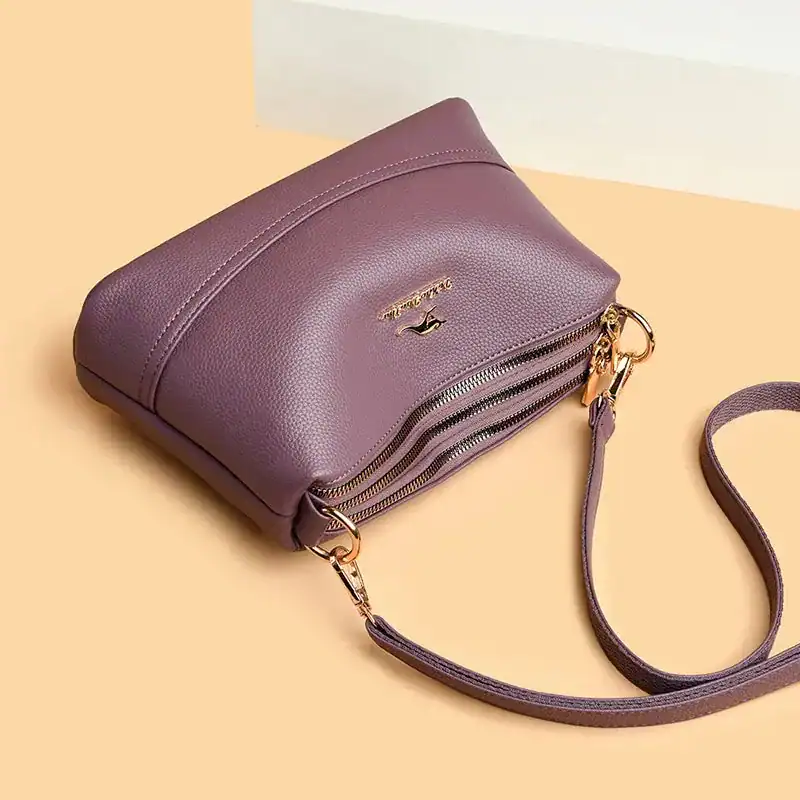 Cognac liten crossbody axelväska i lila läder med dubbel dragkedja och axelrem.