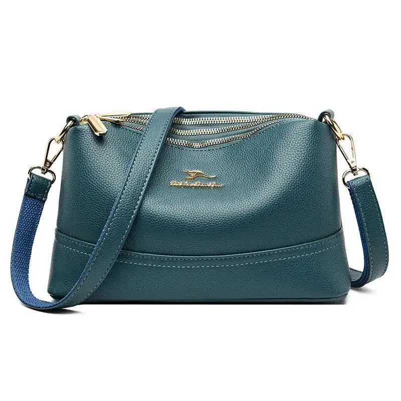 Cognac liten crossbody axelväska i mörkgrön läder med guldtonade dragkedja och axelrem.
