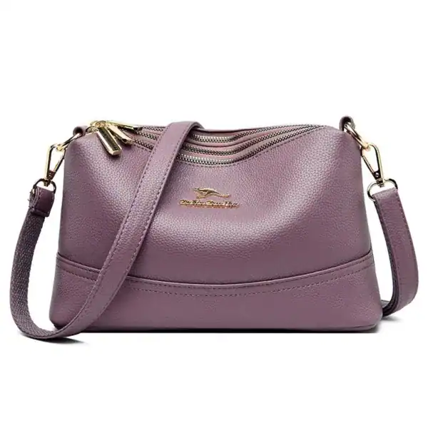 Liten cognacfärgad crossbody axelväska med guld dragkedja och axelrem.