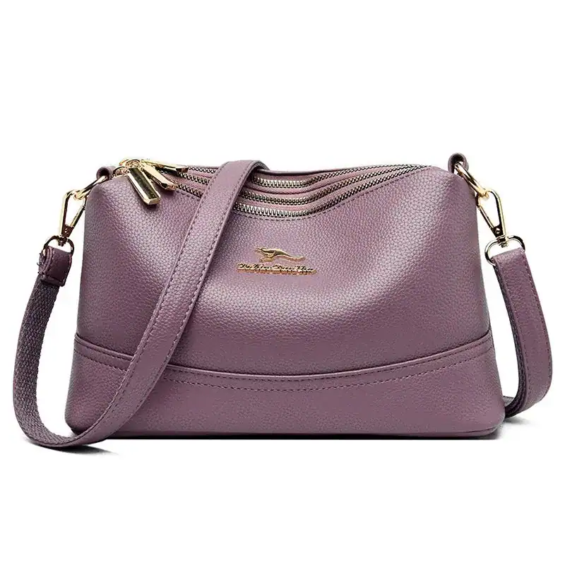 Liten cognacfärgad crossbody axelväska med guld dragkedja och axelrem.