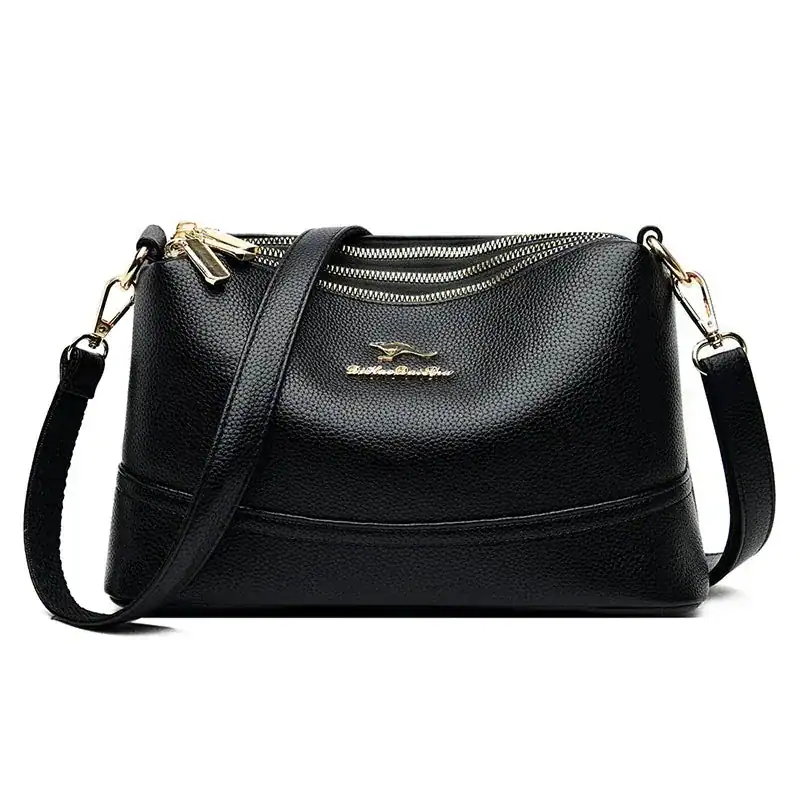 Svart läder crossbody väska med guld dragkedja och axelrem.
