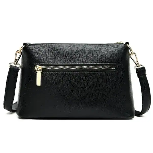 Svart cognac liten crossbody axelväska med guld dragkedja och axelrem.