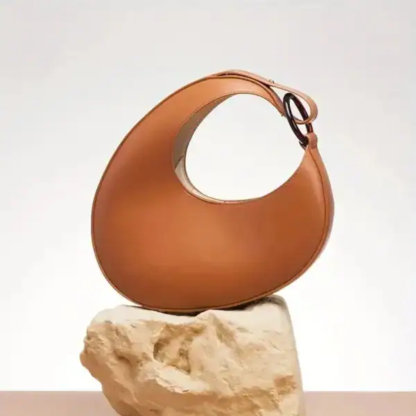 Cognacfärgad halvmånsväska i läder, modern design, elegant axelväska för kvinnor.