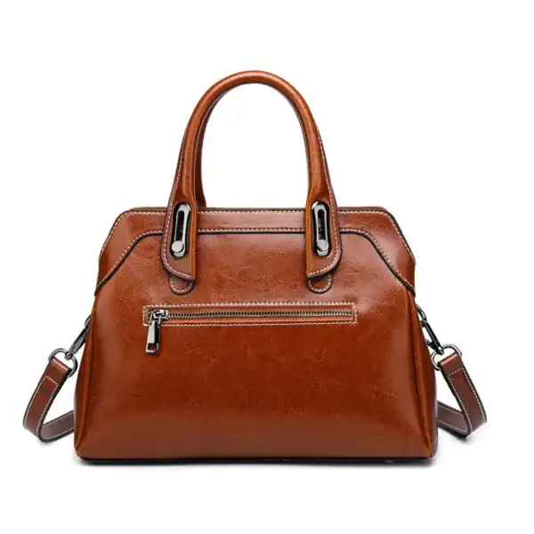 Cognacfärgad handväska med axelrem, läderliknande material och frontficka.