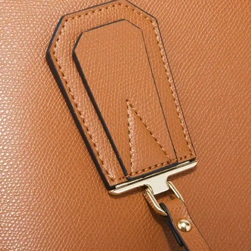 Dammrosa Axelväska detalj, läderplåt med svart sömmar och metallficka.