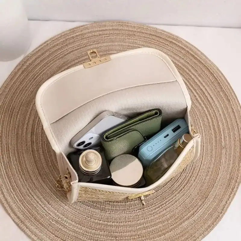 Flätad clutch med läderrem, innehåller mobil, plånbok och powerbank.