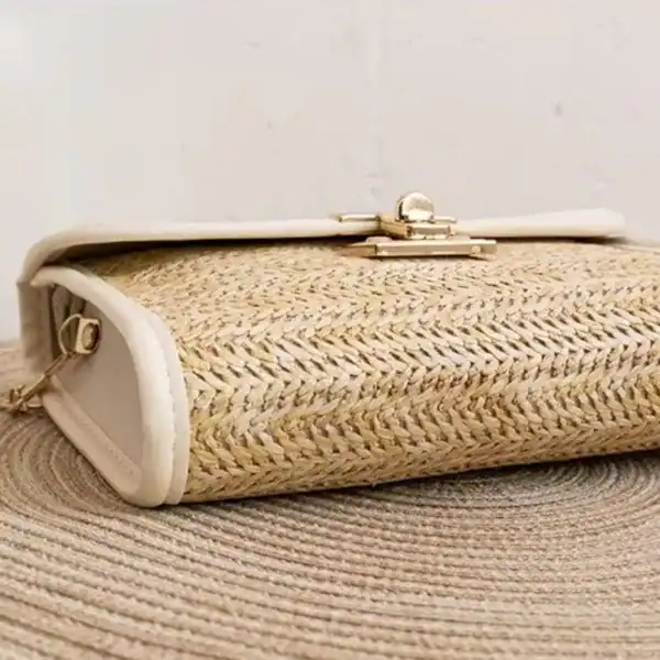Flätad clutch med läderrem och guldtonad spänne, perfekt för sommar.