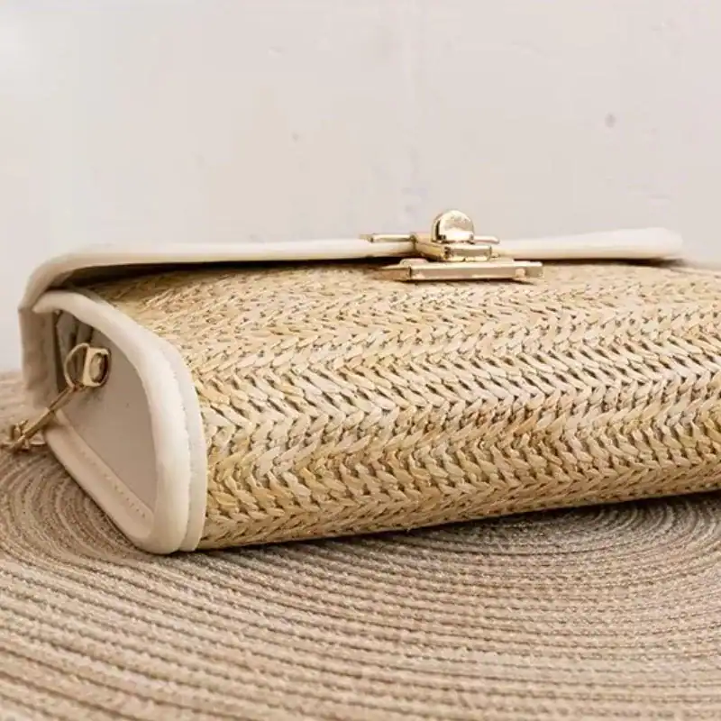 Flätad clutch med läderrem och guldtonad spänne, perfekt för sommar.