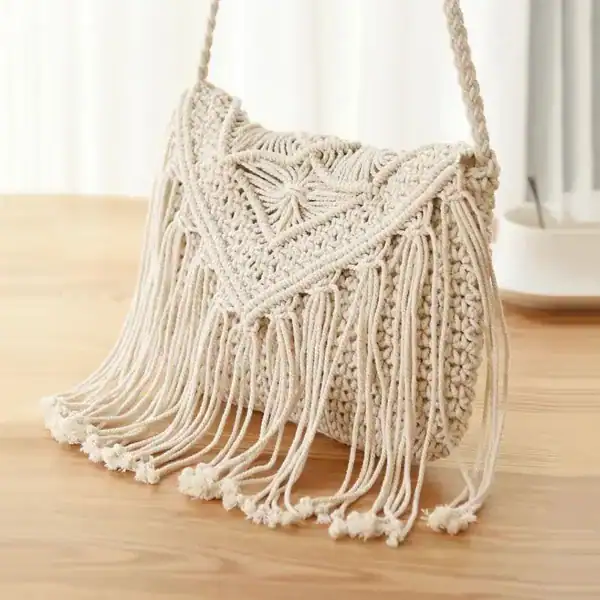 Flätad handväska i beige med fransar och hängslinga.