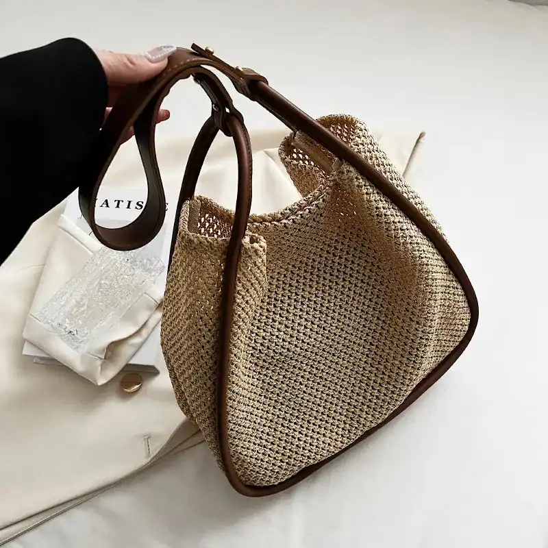Beige flätad shoppingväska med bruna handtag och vävad textur.