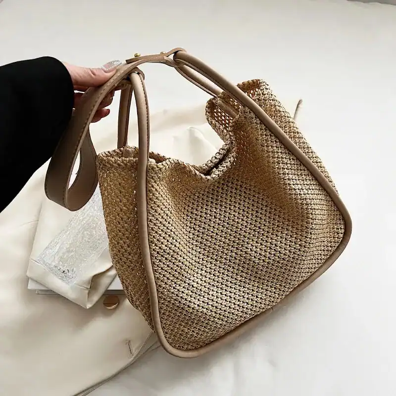 Beige flätad shoppingväska med läderhandtag och strukturerad väv.