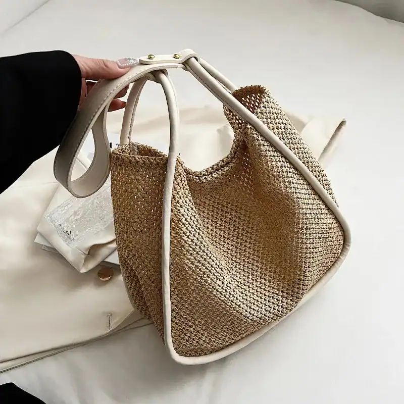 Beige flätad shoppingväska med vitt handtag, lätt och trendig för sommar.