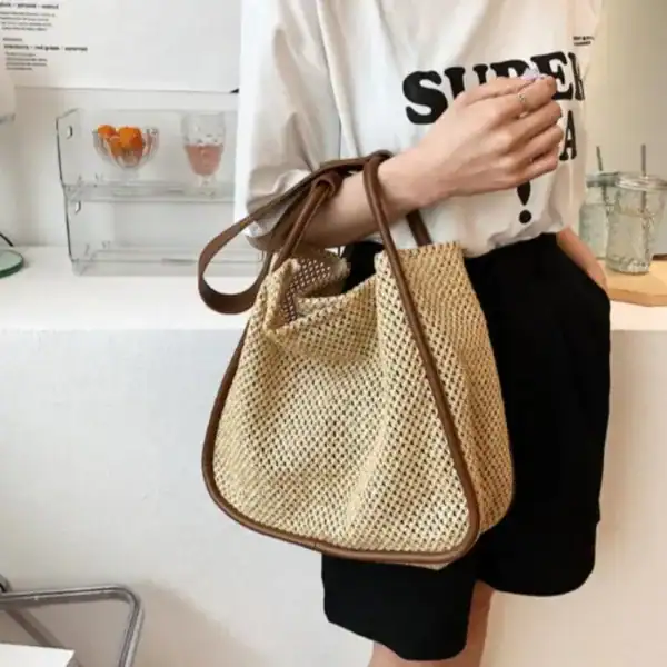 Beige flätad shoppingväska med brun läderhandtag, trendig och lätt att bära.