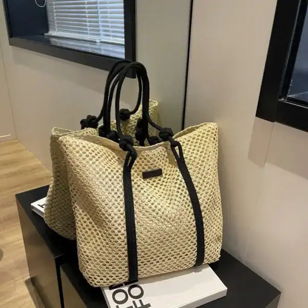 Flätad shoppingväska med svart rem och öppen topp, lämplig för sommar och strand.