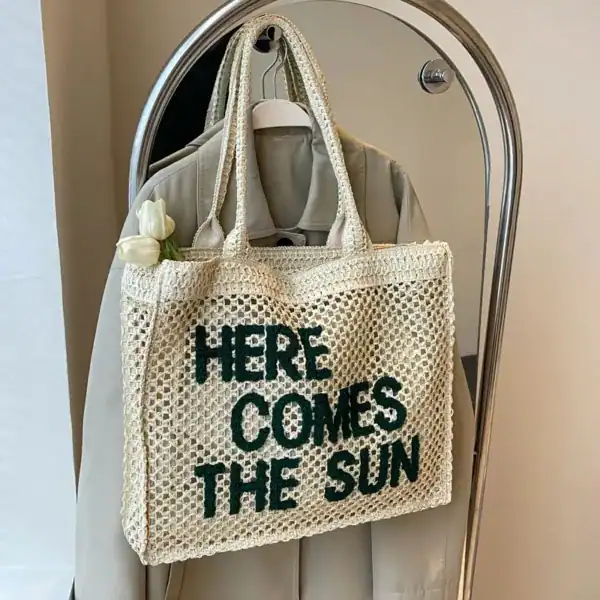 Flätad väska med text 'Here Comes The Sun', trendiga sommarväskor.