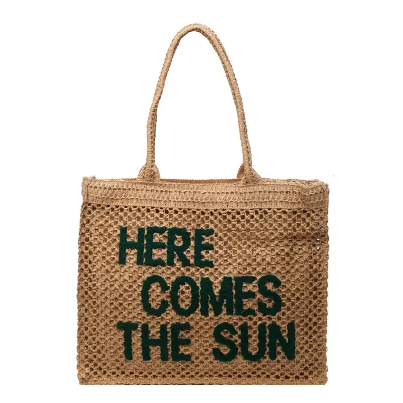Flätad väska med text 'HERE COMES THE SUN', trendiga sommarväskor.