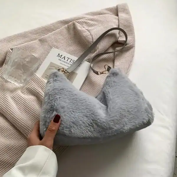 Grå fluffig axelremsväska med mjuk pälsliknande yta och elegant axelrem.