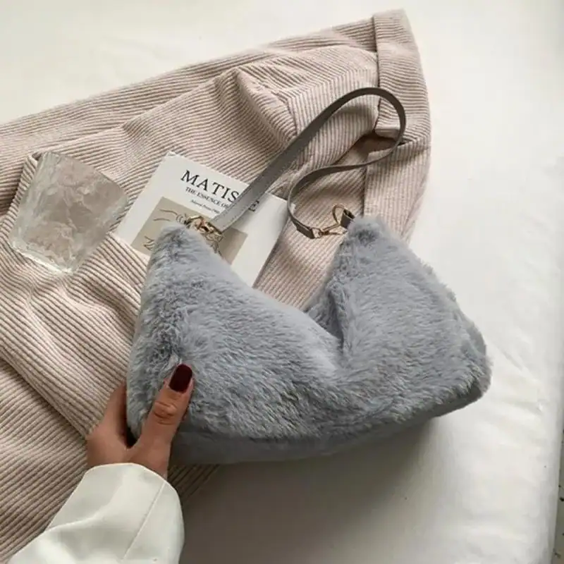 Grå fluffig axelremsväska med mjuk pälsliknande yta och elegant axelrem.