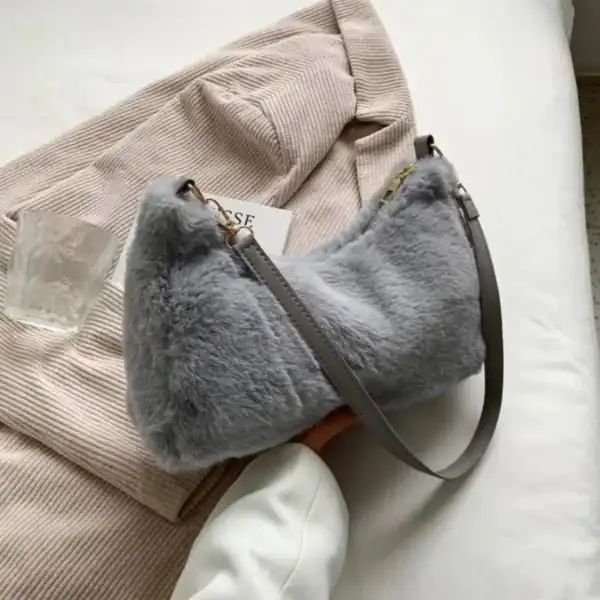 Grå fluffig axelremsväska med plüssig yta och läderrem.