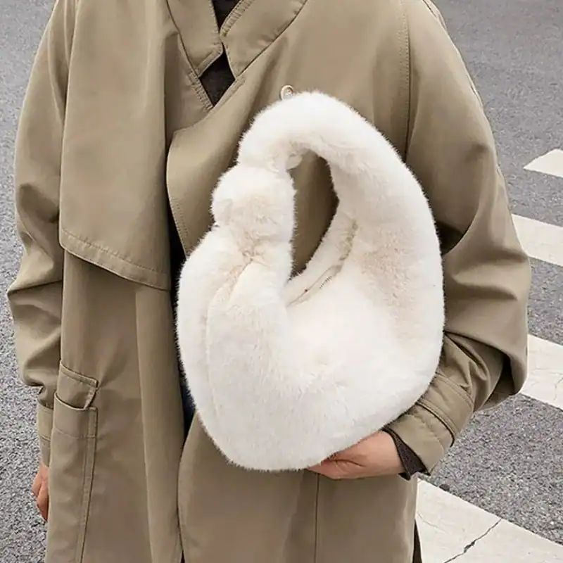 Grå fluffig hobo axelväska med mjuk pälsliknande yta och rund form.