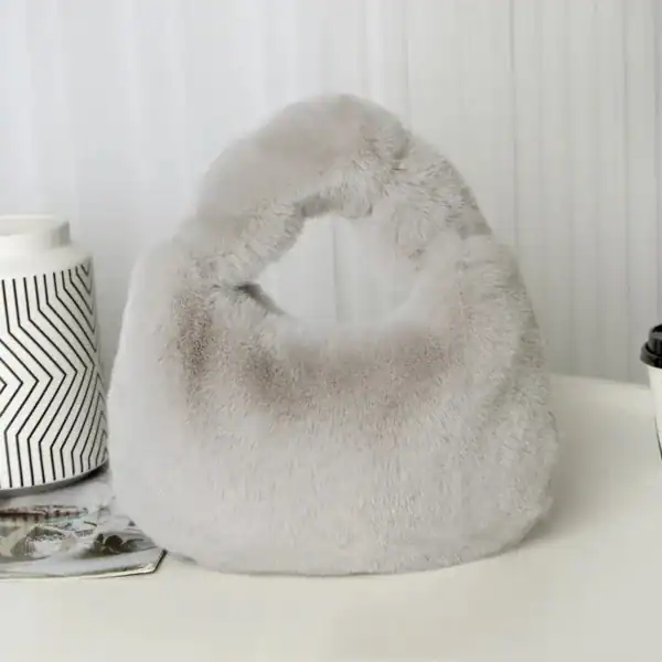 Grå fluffig hobo axelväska med runt handtag och mjuk pälsliknande yta.