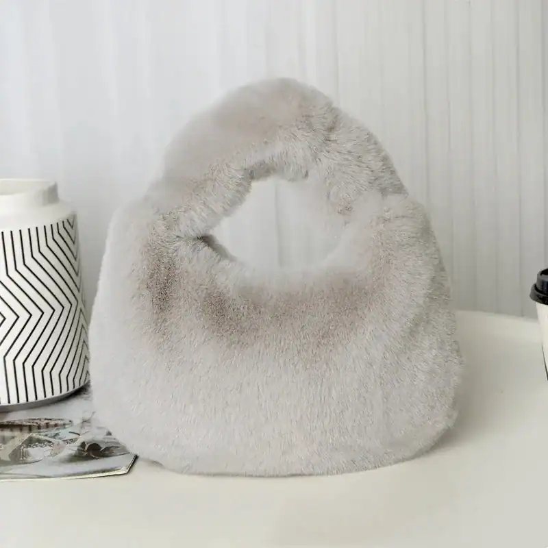 Grå fluffig hobo axelväska med runt handtag och mjuk pälsliknande yta.