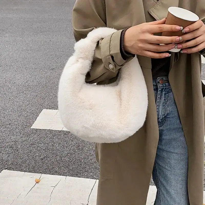 Grå fluffig hobo axelväska med mjuk pälsdetalj och rund form.