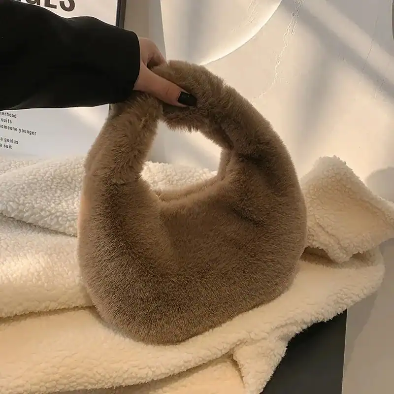 Grå fluffig hobo axelväska med mjuk pälsliknande yta och runt handtag.