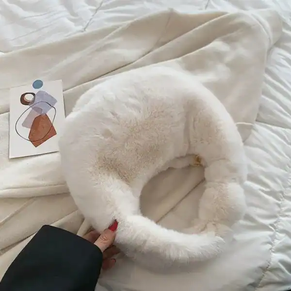 Grå fluffig hobo axelväska med mjuk pälsliknande yta och rund form.