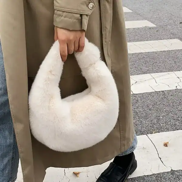 Grå fluffig hobo axelväska med mjuk pälsliknande yta och runt handtag.