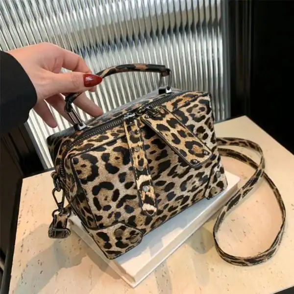 Grå leopard mönstrad axelväska med axelrem och handtag.