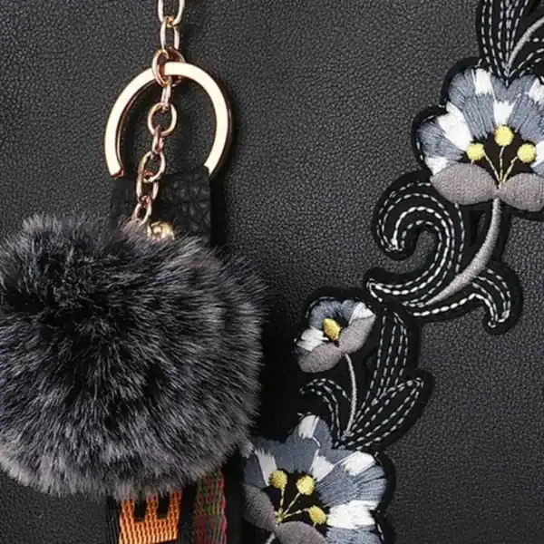 Grå svart handväska med blommor och pärla, närbild på broderi och pärla.