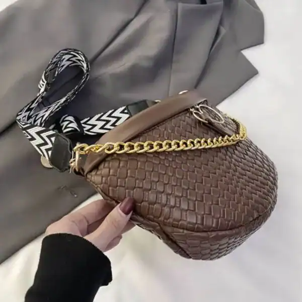 Brun flätad midjeväska med guld kedja och svart-vit mönstrad axelrem.