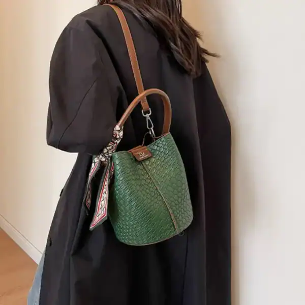 Grön hinkväska med sköldpadda mönster och skinnremmar.