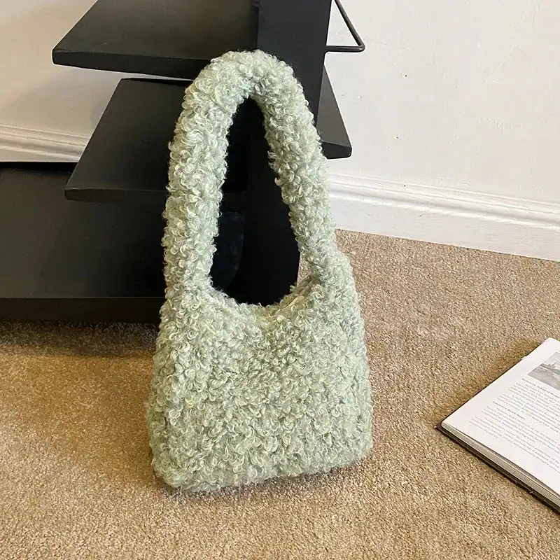 Grön teddyväska med fluffig textur och runt handtag.