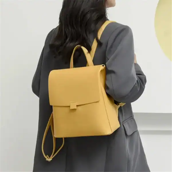 Gul ryggsäck med korta axelremmar, läderliknande material och enkel design.