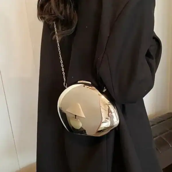 Guld clutch med silverfärgad kedja, reflekterande yta och elegant design.
