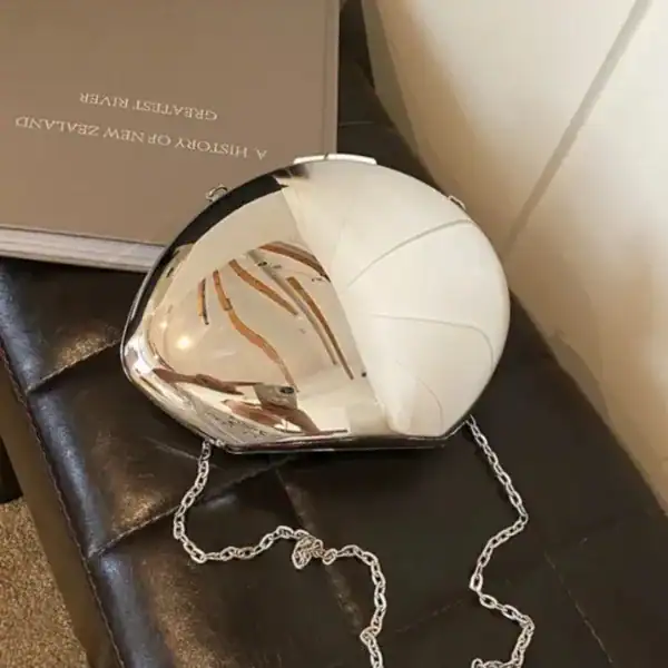 Guld clutch med spegelblank yta och kedjehängare.