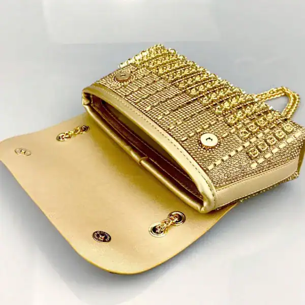 Guld kuvertväska med strass och öppen inre, perfekt för festliga tillfällen.