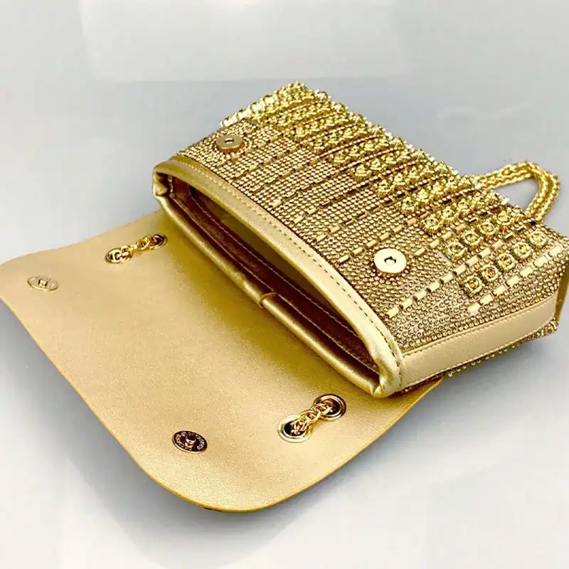 Guld kuvertväska med strass och öppen inre, perfekt för festliga tillfällen.