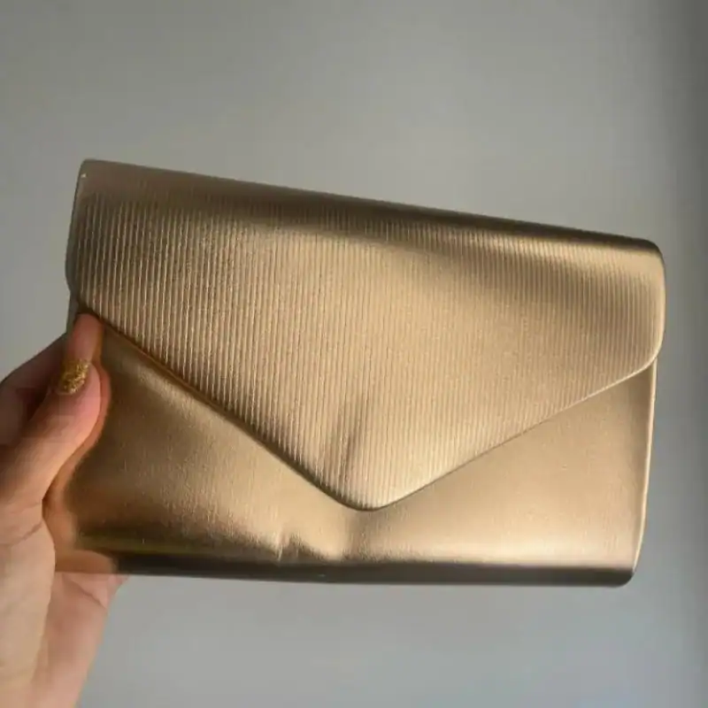 Guld satinclutch med strukturerad yta och envelope-design.