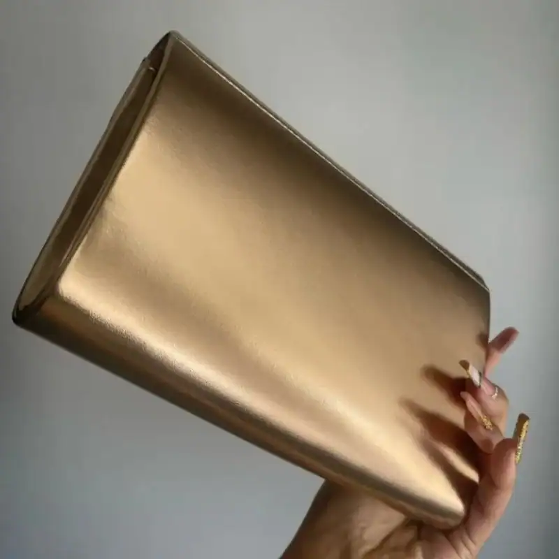 Guld satinclutch i handen, elegant och glittrande för festliga tillfällen.